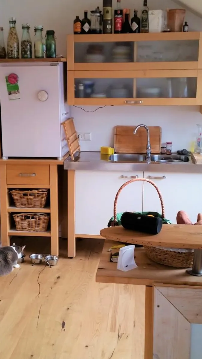 Eine gemütliche Küche in einer Dachgeschosswohnung mit hellen Holzschränken und offenen Regalen, die für eine warme Atmosphäre sorgen.