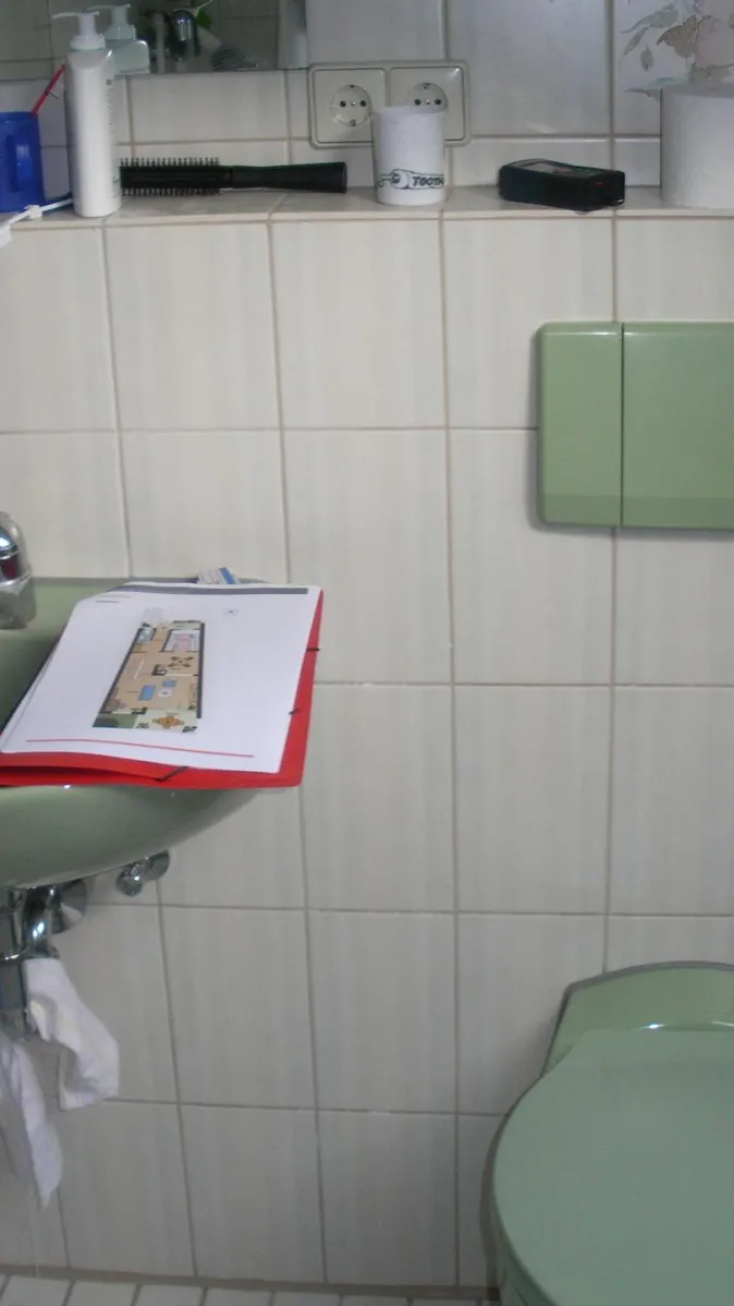 Ein kleines Badezimmer mit weiß gefliesten Wänden und einer grünen Toilette sowie einem dazu passenden Waschbecken.