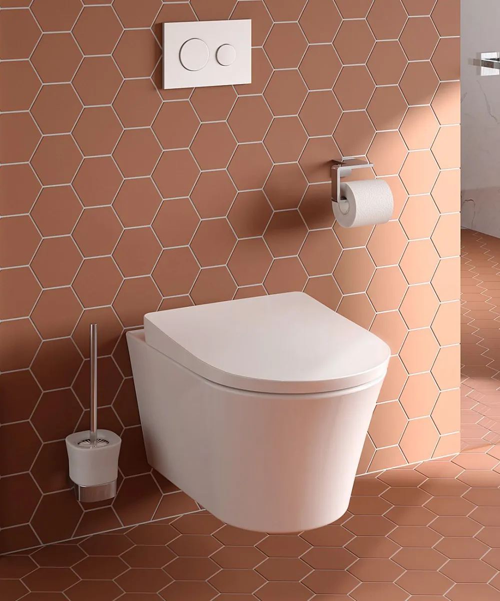 In einem zeitgemäß designten Bad ist ein TOTO GP Wand-WC an einer Wand mit terrakottafarbenen Sechseckfliesen montiert.