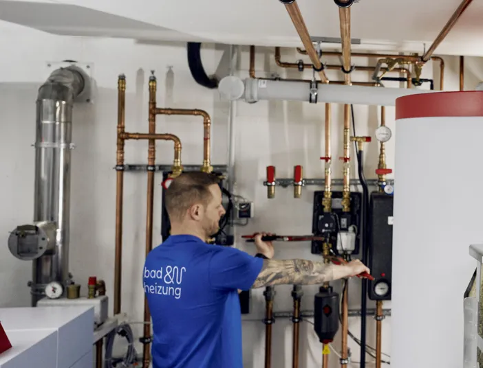 Zwei Anlagenmechaniker montieren einen Heizkessel.