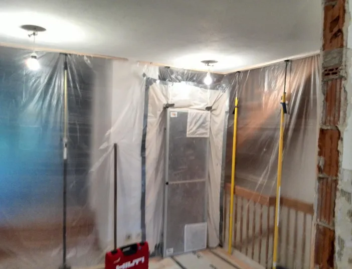 Ein Innenraum während Renovierungsarbeiten ist mit durchsichtiger Folie abgedeckt, um Staubschutz zu bieten.