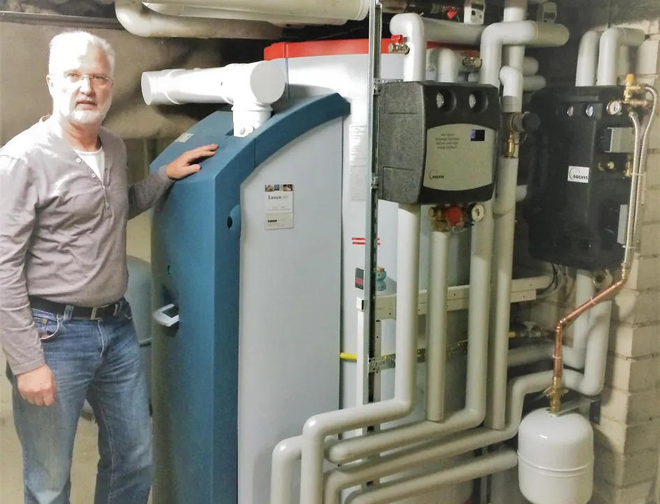 Ein Mann steht in einem Heizraum neben einer komplexen Gasheizungsanlage.