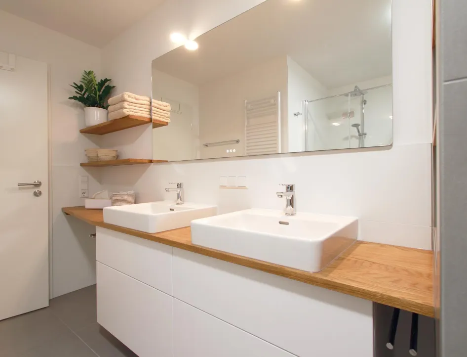 Modernes Badezimmer mit Doppelwaschtisch, Holzarbeitsplatte und großzügigem Spiegel. 