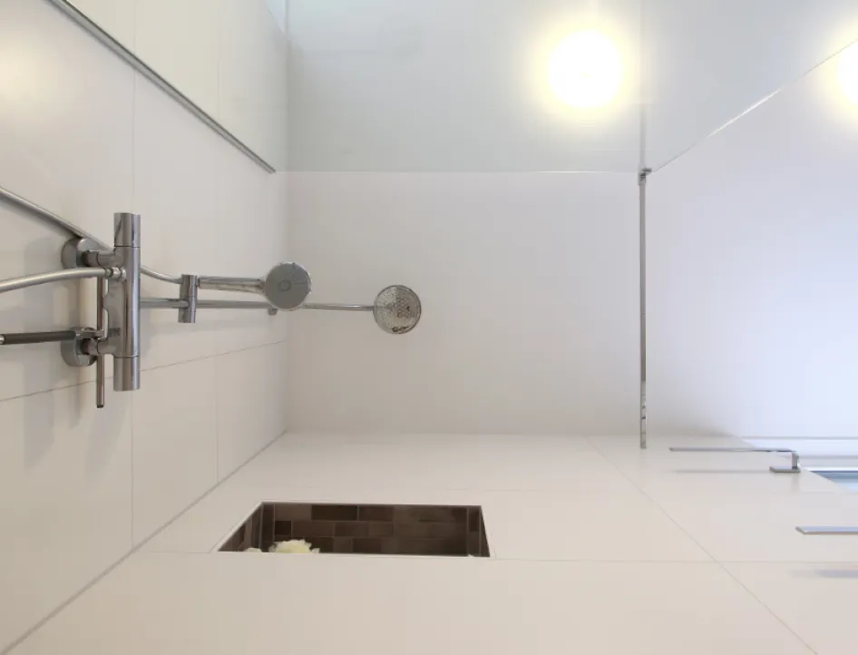 Ein modernes Duschsystem mit einer eleganten Edelstahlarmatur und zwei Duschköpfen, die an einer schlichten weißen Wand montiert sind.